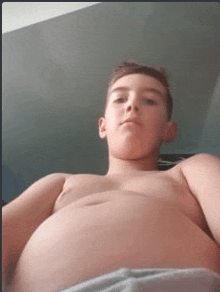 a shirtless boy is taking a selfie with his huge belly .