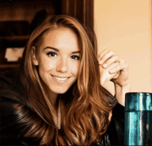 a woman with long brown hair is smiling and holding her hand to her face