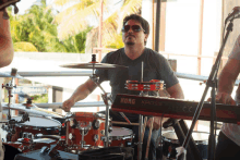 a man playing drums next to a korg kross keyboard