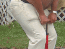 a man in white pants is holding a red hose