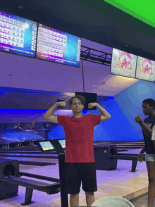 a man in a red shirt flexes his muscles in front of a scoreboard that says 32 on it