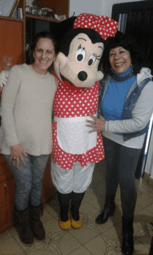 two women are posing for a picture with a minnie mouse mascot