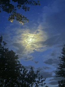 a full moon shines through the clouds in a blue sky