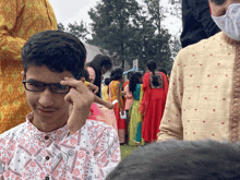 a boy wearing glasses is standing in a crowd of people