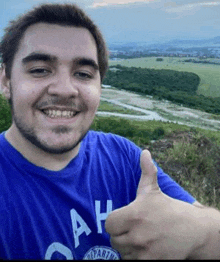 a man in a blue shirt is giving a thumbs up sign .