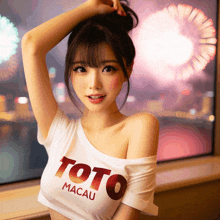 a woman wearing a toto macau t-shirt stands in front of a window