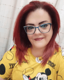 a woman with red hair wearing glasses and a yellow shirt with mickey mouse on it