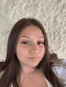 a woman with long brown hair is wearing a white shirt and necklace