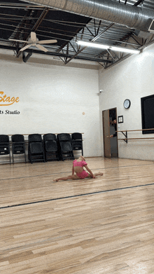 a little girl is doing splits in a dance studio with a sign that says stage