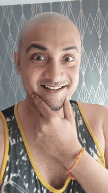 a man with a shaved head and a beard is smiling with his hand on his chin