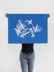 a woman is holding a blue poster with white feathers on it over her head