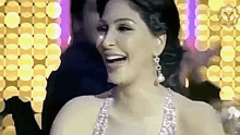 a woman in a dress and earrings is laughing in front of a crowd .