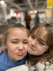 two little girls are making funny faces for a picture