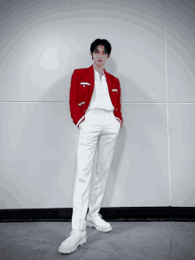 a man in a red jacket and white pants is standing in front of a wall