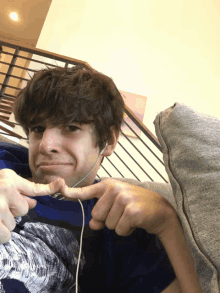 a young man wearing headphones is sitting on a couch making a funny face