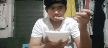 a young boy is eating from a bowl with a spoon in front of a calendar that says ' food ' on it