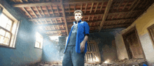 a man in a blue shirt is standing in a room with a wooden ceiling