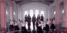 a group of women are dancing in a large room with a lot of windows .