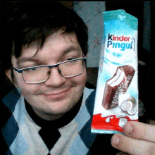 a man is holding a kinder pingui bar in his hand