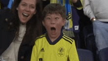 a young boy wearing a yellow adidas jersey makes a funny face