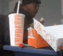 a man is sitting at a table with a cup that says ' chicken ' on it