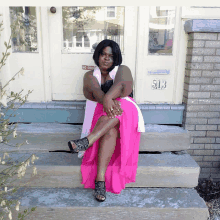 a woman in a pink skirt sits on the steps of a building with the number 513 on it