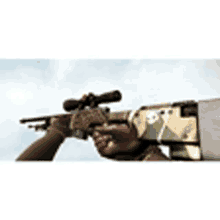 a person is holding a sniper rifle with a scope on it .