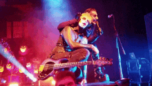 a man is sitting on another man 's shoulders while playing a guitar on stage .