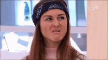 a woman wearing a bandana on her head is making a face .