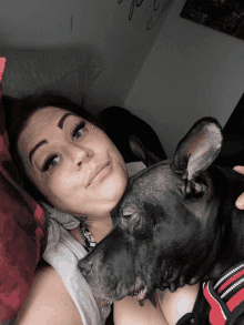 a woman laying on a bed with a black dog looking at her