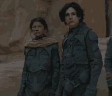 a man and a woman standing next to each other in a desert