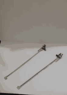 a pair of metal rods with holes in them are sitting on a white surface