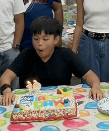 a boy is blowing out candles on a birthday cake that says happy birthday