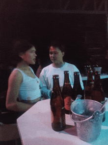 a man and a woman are sitting at a table with bottles of beer on it