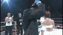 a man in a suit is hugging a woman in a bikini in a boxing ring ..