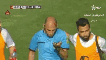 a referee is standing next to a man with a bottle of water on a soccer field .