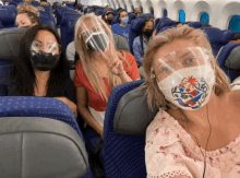 a group of people wearing face masks and face shields on a plane