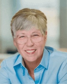 a smiling woman wearing glasses and a blue shirt