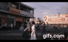 a group of people are walking down a street in front of a building with a lot of signs .