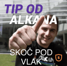 a man giving a thumbs up in front of a sign that says tip od alka na skoc pod vlak