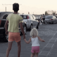 a man and a little girl are holding hands in a parking lot with la guarimba festival in the background