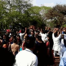 a crowd of people are gathered in a park with trees in the background and a sign that says ' a ' on it