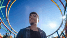 a young man is standing in front of a roller coaster at an amusement park