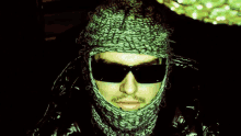 a man wearing sunglasses and a knitted scarf around his head