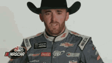 a man in a cowboy hat is wearing a nascar jacket