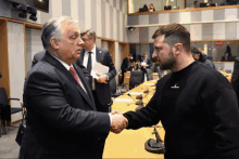 a man wearing a black sweatshirt that says ' salomon ' on it shakes hands with another man