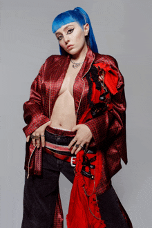 a woman with blue hair wearing a red jacket and black pants