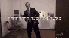 a man in a suit and tie is dancing in a room with hebrew writing on it