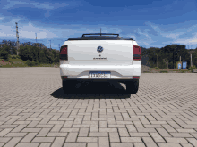 a white volkswagen saveiro is parked on a brick parking lot