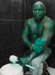 a man with green paint on his face is sitting on a toilet holding a toilet brush